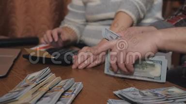一个年迈的家庭数着坐在房子桌子旁的现金储蓄。